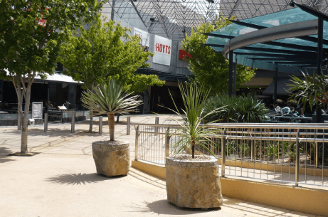 Large natural stone planter bases placed in an urban commercial outdoor area with trees and paved pedestrian walkways